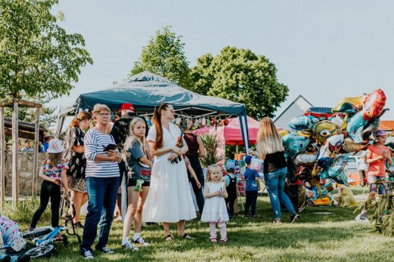 A lively outdoor gathering with families enjoying balloons and a sunny day.