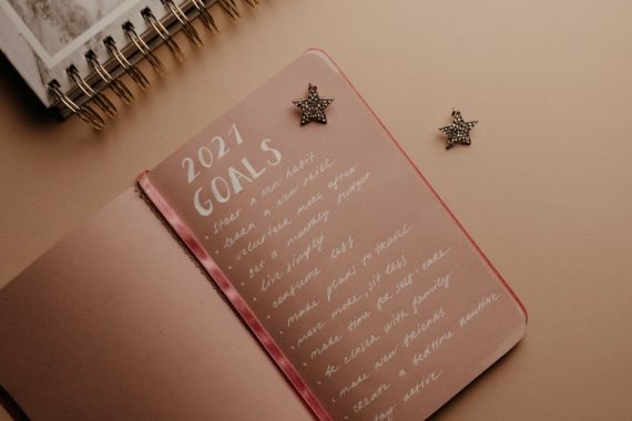 Top view of a 2021 goals notebook with handwritten list and star decorations, ideal for planning inspiration.